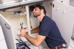 professional plumber checking kitchen sink for leaks